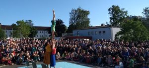 three women perform an acrobalance trick in front of a large audience.