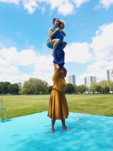 3 acrobats perform an acrobalance trick. 2 women on the shoulders of a third woman