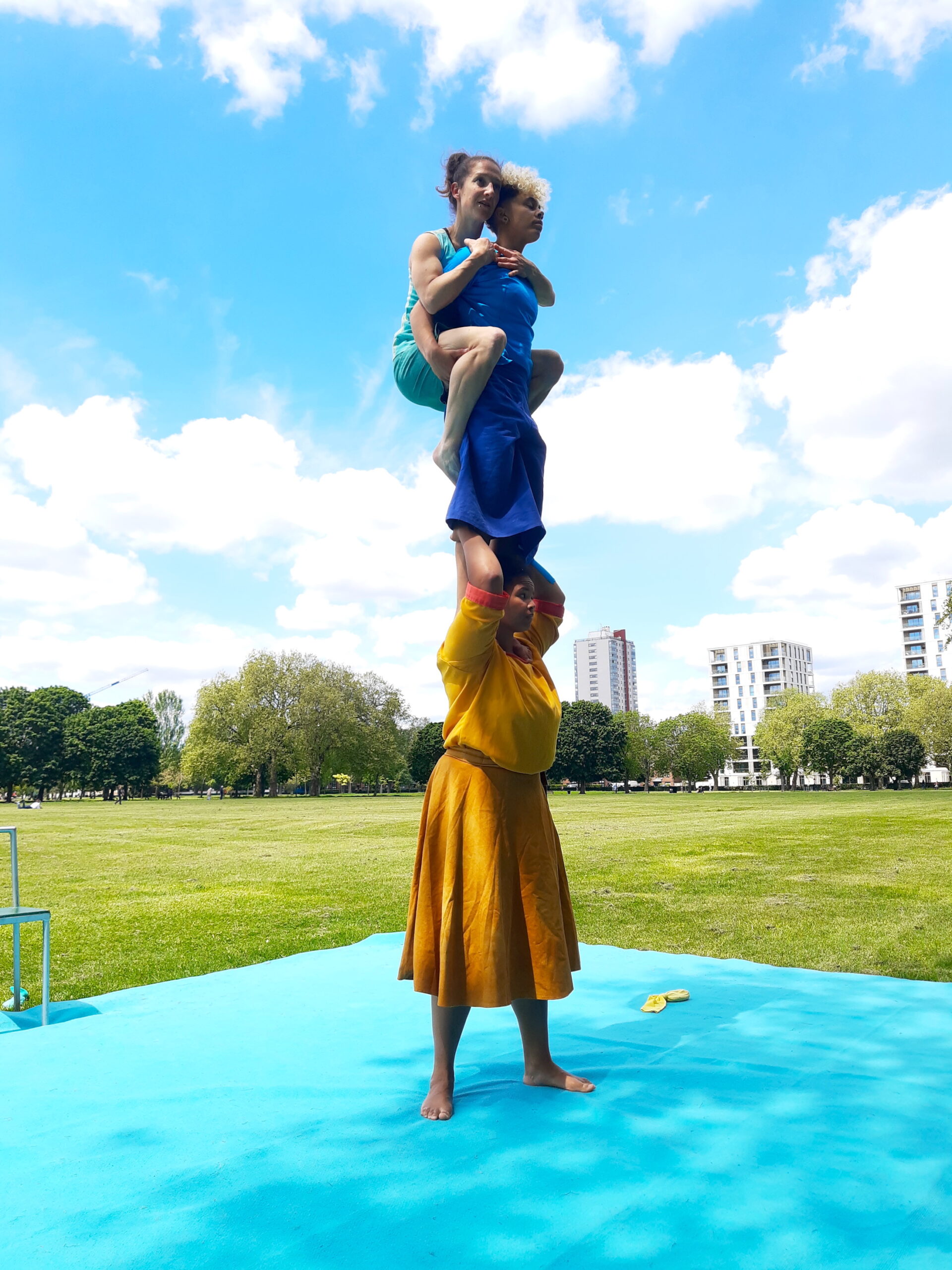 3 acrobats perform an acrobalance trick. 2 women on the shoulders of a third woman