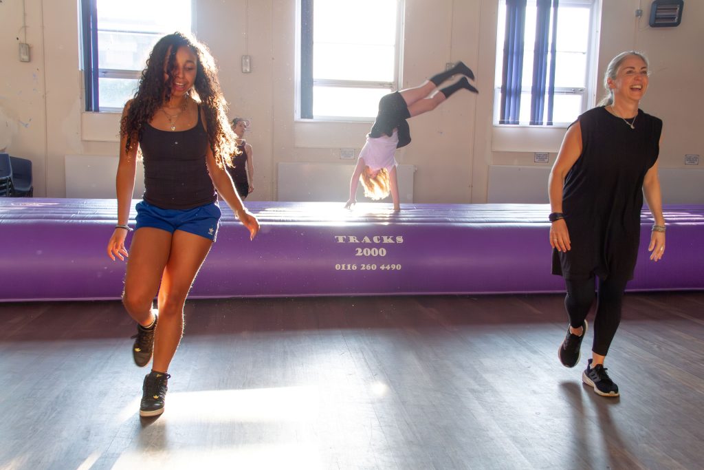 Two people dancing in a hall. Behind them a child jumps on an inflatable.